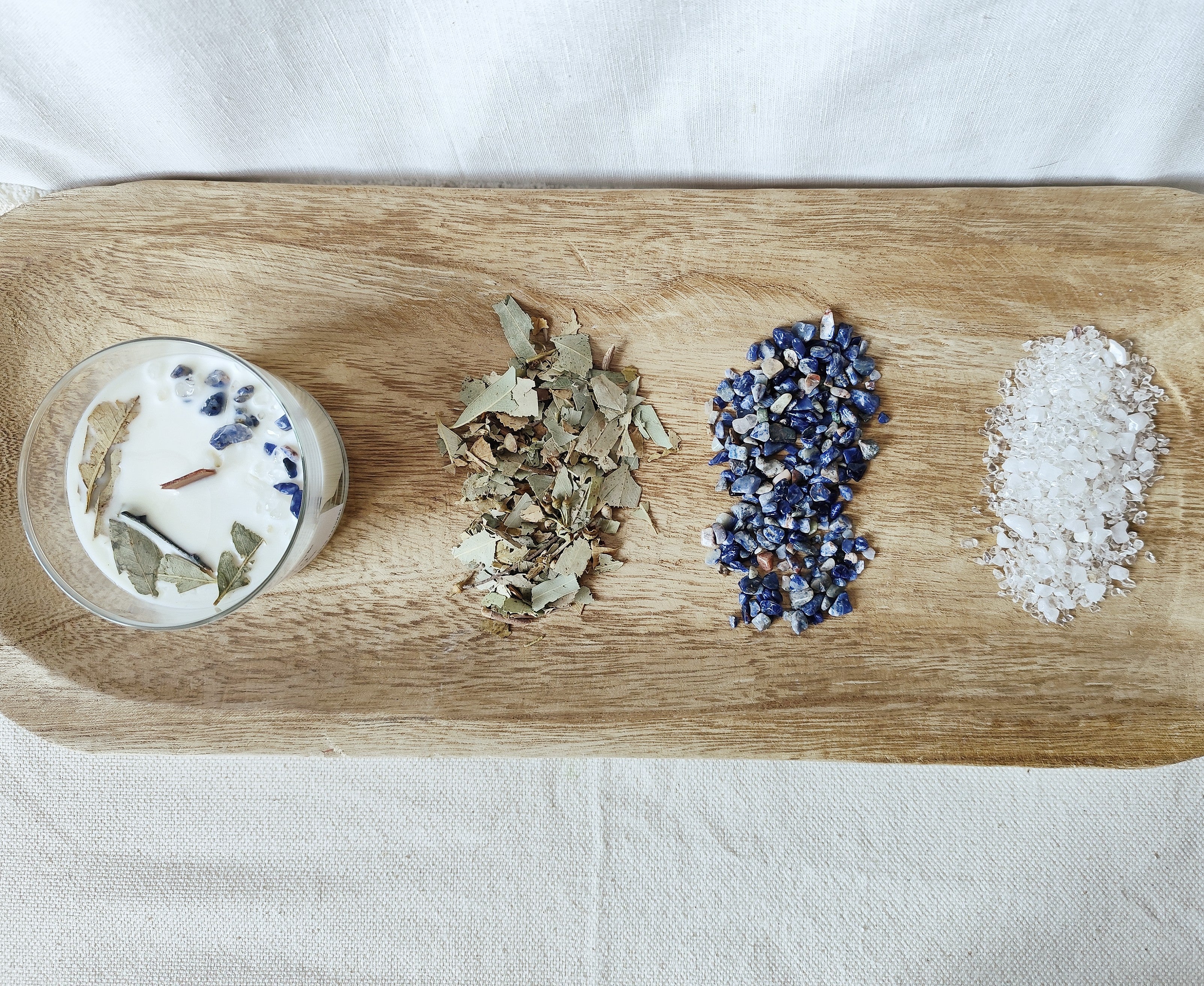Vela de soja en bandeja de madera con piedras naturales y plantas naturales